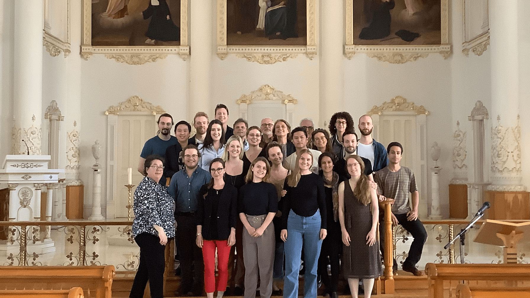 La cohorte de l'Académie réunie dans le chœur d'une église blanche ornée de tableaux.