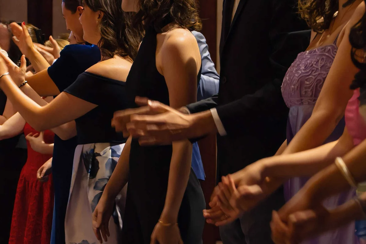 De jeunes chanteurs en tenue de concert, mains levées, baignés d'une lumière chaude.