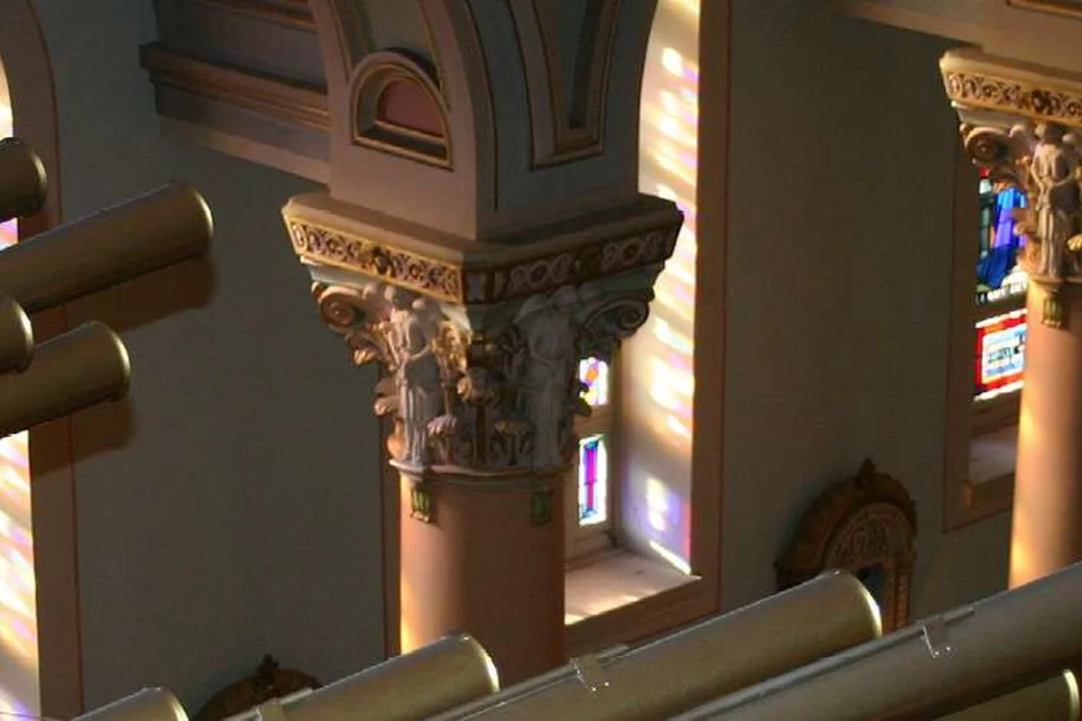 Intérieur de l'église des Saints-Anges, avec ses tuyaux d'orgue et ses colonnes dans une lumière chaude.